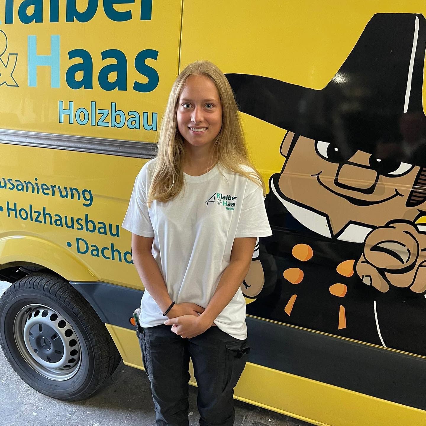 Azubi vor dem Klaiber & Haas Firmenbus mit Zimmermann-Maskottchen